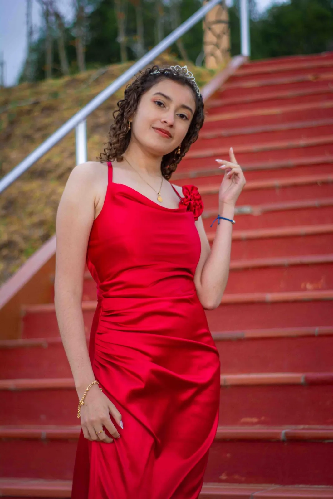 Quinceañera con vestido rojo de satín frente a escaleras rojas