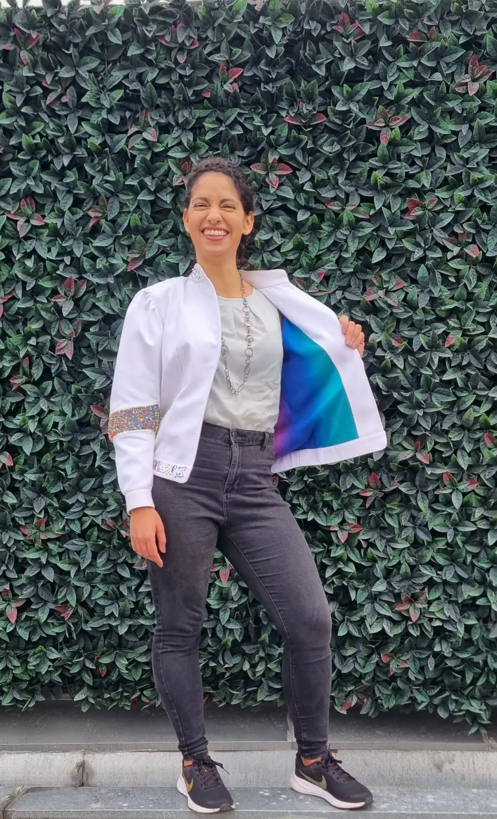 Mujer de pie con la chaqueta blanca abierta que muestra el interior azul y violeta