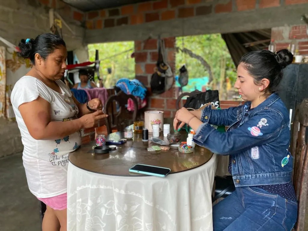 Dos mujeres sentadas a una mesa con pequeños objetos